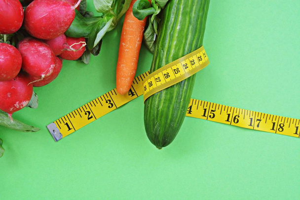 Vegetales crujientes frescos envueltos con una cinta métrica sobre una base de einfabrigen - concepto para una alimentación saludable para perder peso
 - Foto, Imagen