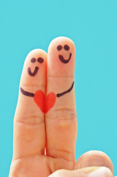 Два лица были нарисованы на указательном пальце и средний палец одной руки и сердце соединяет два - символ интимных отношений и любви
  - Фото, изображение