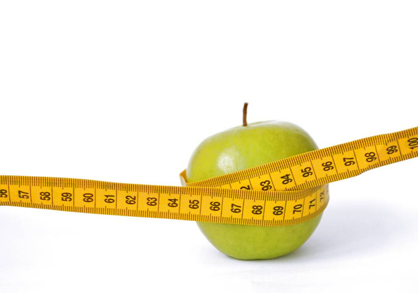 A yellow measuring tape was wrapped around an apple, concept for dieting and slimming due to health with space for text or other elements - Photo, Image