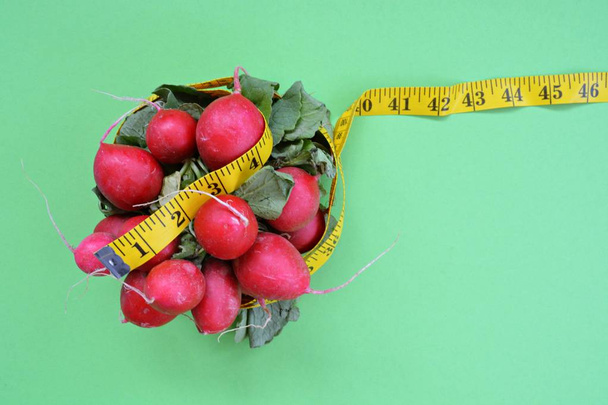 アインファブリゲンベースに横たわる測定テープで包まれた新鮮なカリカリ野菜 - 体重を減らす健康的な食事のためのコンセプト - 写真・画像