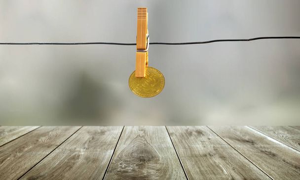 Goldener Bitcoin hängt mit orangefarbener Wäscheklammer an Metallschnur mit Bokeh-Hintergrund, Urlaubskonzept - Foto, Bild