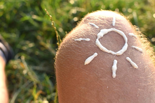 Konzept zum Schutz vor der Sonne an heißen Strandtagen mit einem männlichen Fuß mit Fußkettchen  - Foto, Bild