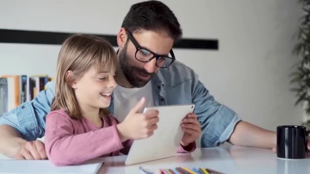 Handsome young father with his daughter using they digital tablet at home. - Кадри, відео