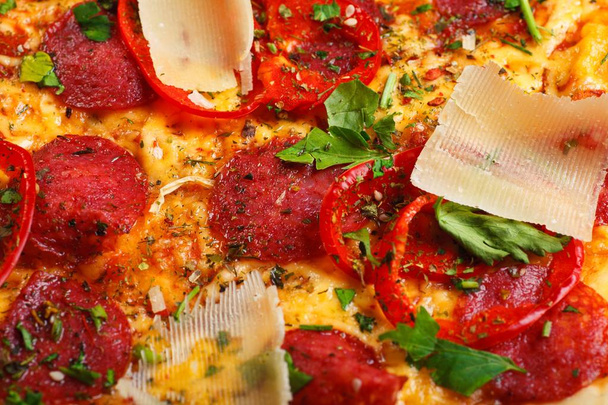 パルメザンチーズ、トマト、サラミ、ペパロニ、グリーンバジルのピザイタリアン、キノコ、赤唐辛子、チェリートマトで飾られた茶色のテーブル - 写真・画像