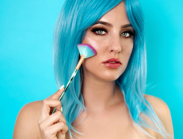 Portrait of beautiful young woman with blue hair holding make up brush  - Фото, изображение