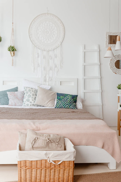 Green, beige pillow on bed in bedroom with pastel colored bedsheets on bed. stylish white apartment design in lagom style.Stylish scandinavian white interior with bed, tropical plant, cozy blanket. - Foto, immagini