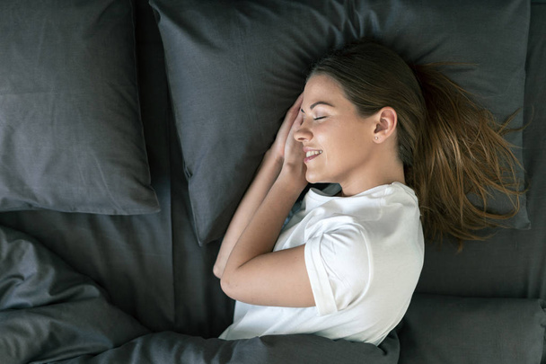 Young adult woman sleeping on bed in morning - Photo, Image