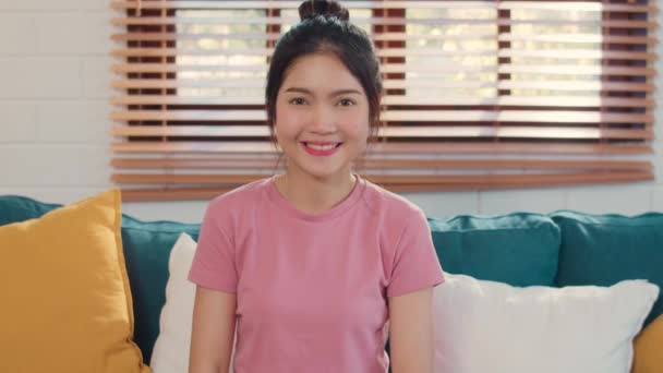Portrétní Asijská Čínská žena cítila šťastný úsměv doma. Japonská dívka relaxovat s úsměvem a dívat se na kameru, zatímco v obývacím pokoji u domu v obýváku se pojí pohovka. - Záběry, video