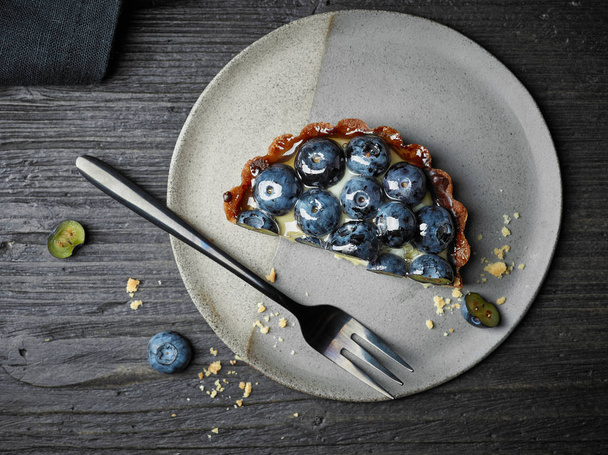 blueberry tart on dark wooden table - Фото, изображение