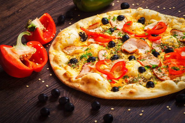 Vegetarische Pilze italienische Pizza mit geschmolzenem Käse, rotem Pfeffer, Mais, Zwiebeln, schwarzen Oliven und frischen Kräutergewürzen auf einem braunen Tisch mit Pilzen, schwarzen Oliven, rotem grünen Pfeffer und Rucola dekoriert - Foto, Bild
