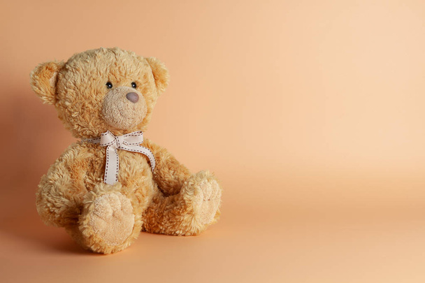 Soft warm cute brown teddy bear on color background. Isolated. Soft coral, yellow, brown background. Copy space for text. - Photo, Image