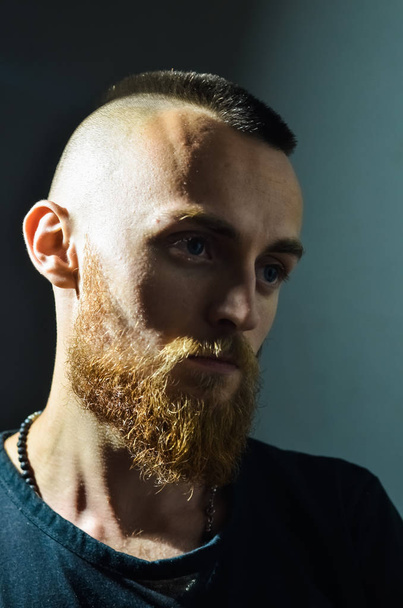 Portrait of young European hipster with fair skin and trendy ginger beard. Fashionable undercut hairstyle and handsome face features.  Mohawk hairstyle, iroquois, mohican. - Photo, Image