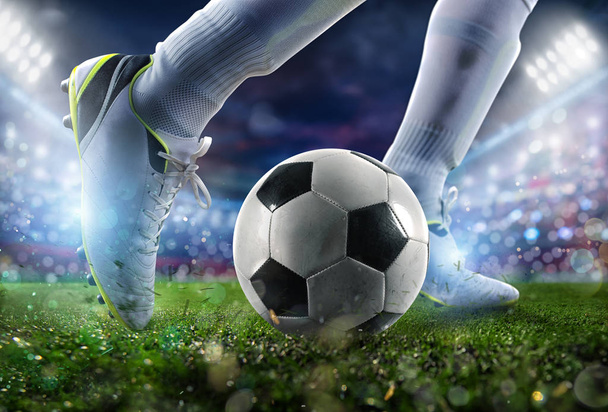 Football scene at night match with close up of a soccer shoe hitting the ball with power. - Photo, Image