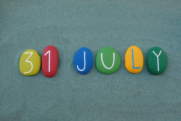 31 July, calendar date composed with multi colored stones over green sand - Photo, Image