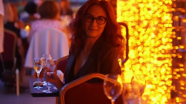 Een flirterige vrouw zittend bij tafel in het buitenrestaurant-het houden van een glas Champagne - Video