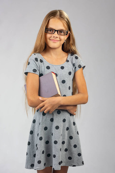Schoolmeisje in glazen staat met een boek in haar handen - Foto, afbeelding
