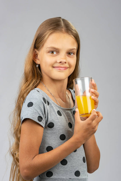 The girl proudly holds a glass of juice - Photo, Image