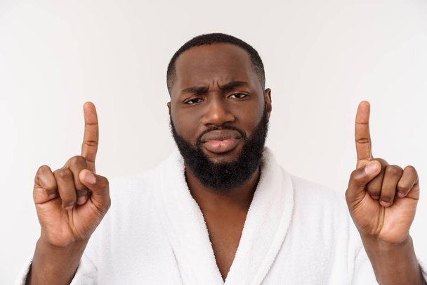 Black guy wearing a bathrobe pointing finger with surprise and happy emotion. Isolated over whtie background. - Fotografie, Obrázek