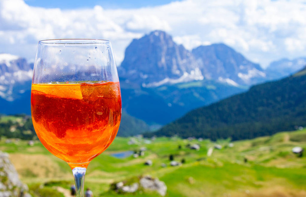 Pohled na tradiční italský alkoholický nápoj Aperol spritz na pozadí barevných italských luk a pohoří Dolomity Alp. vesnice St. Cristina di Val Gardena Bolzano Seceda, Itálie. - Fotografie, Obrázek