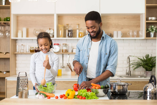Padre e figlia che preparano insalata fresca in cucina
 - Foto, immagini
