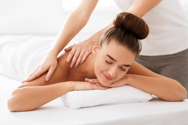 Body massage. Woman enjoying shoulder massage in spa - Foto, Imagem