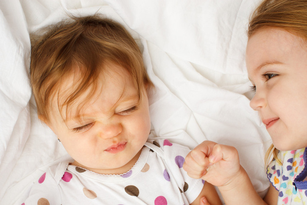 Bebê tolo em lençóis com irmã mais velha
 - Foto, Imagem