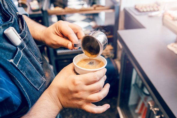Close-up van Barista handen maken cappuccino latte. Ober server gieten warme drank in koffie papier Cup. Klein bedrijf en persoon op het werk concept. - Foto, afbeelding