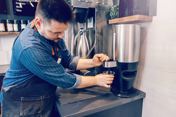 Caucasian handsome bearded man barista making cold iced coffee cappuccino latte. Waiter server pouring drink in plastic transparent cup. Small business and person at work concept. - Valokuva, kuva