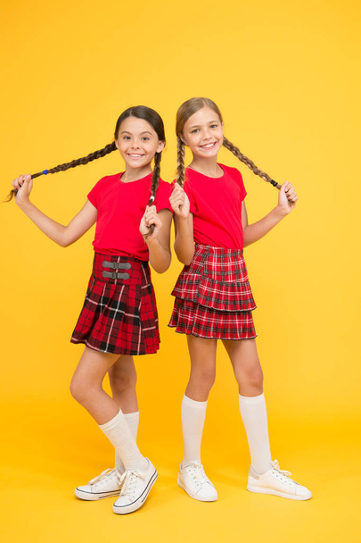 Strong hair. Grow strong and healthy hair. Hair care concept. Beautiful sisters. Children cheerful play with long braided hair. Happy moments. Kids girls sisters best friends in cheerful mood - Photo, Image