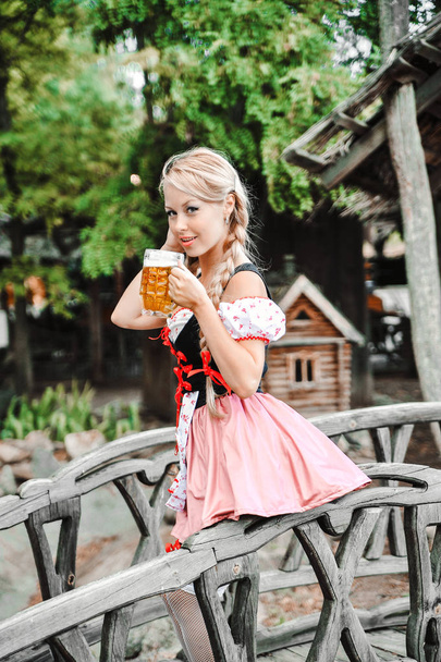 Όμορφη Καυκάσια γυναίκα με μπύρα σε φόρεμα. Φεστιβάλ Octoberfest. - Φωτογραφία, εικόνα