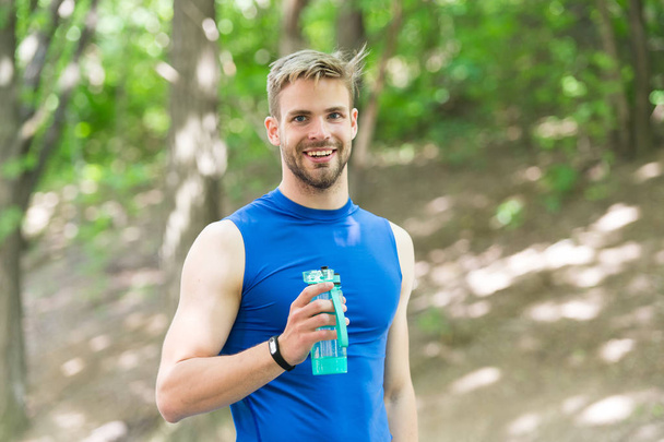happy athletic man with water bottle. Athlete drink water after training in park. body hydration. sport and health. man in sportswear drink water. refreshing vitamin drink after workout. happy health - Foto, afbeelding
