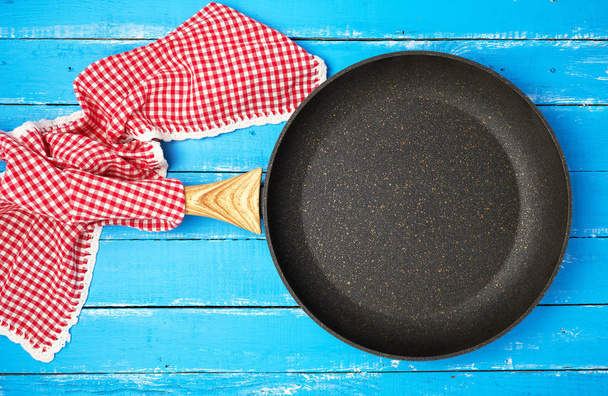 пустая черная круглая сковорода с деревянной ручкой и красной кухней
  - Фото, изображение