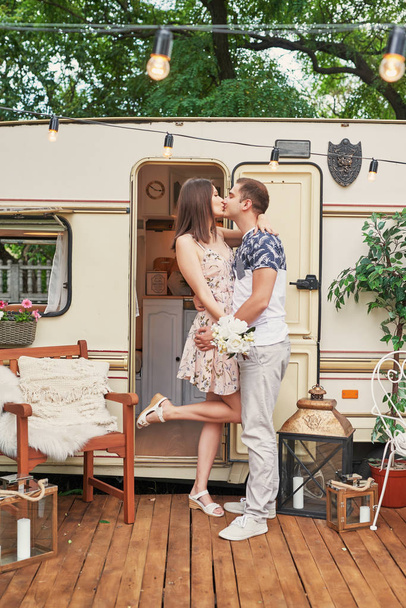 young couple relaxing on a picnic in the summer near the trailer on wheels - Photo, image