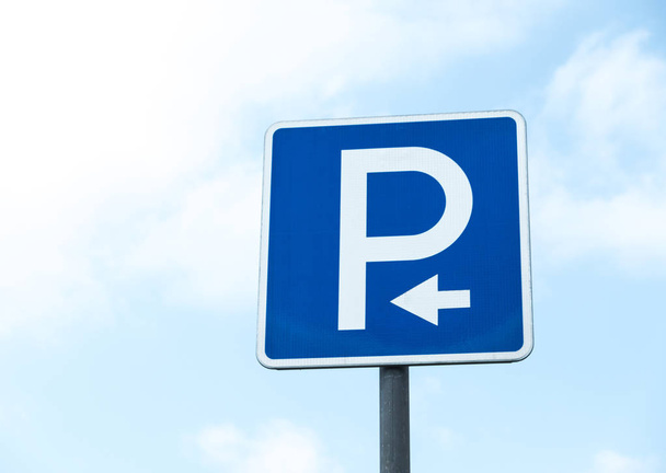 Road sign against the sky. White letter P on a blue background. Sign "Parking". Summer day. - Photo, Image