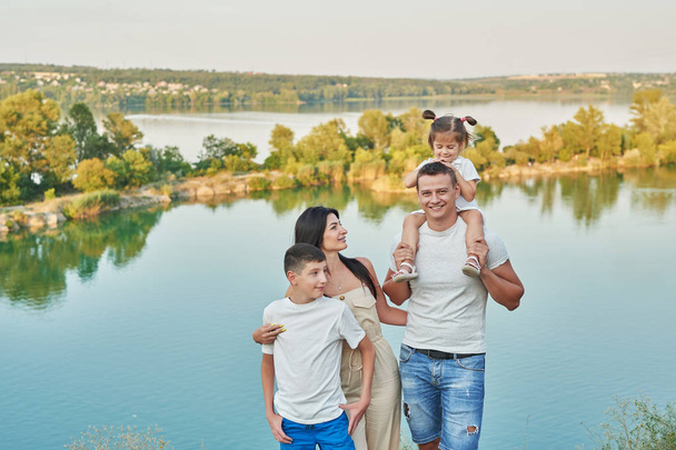 famiglia con figli figlio e figlia in vacanza vicino al lago in estate al tramonto
 - Foto, immagini