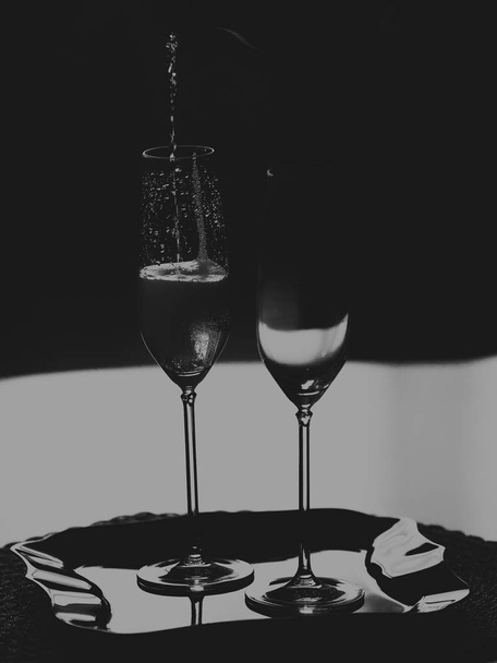 Two tall glasses of sparkling wine. Monochrome - 写真・画像