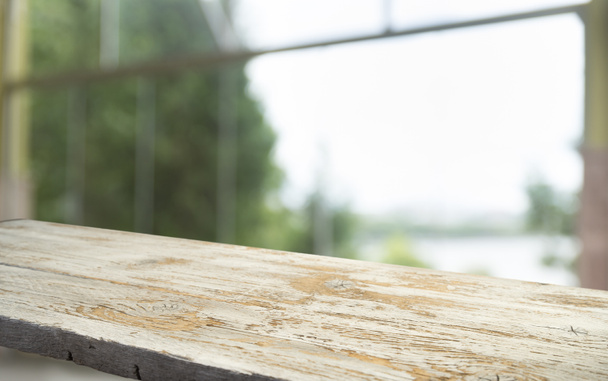 Üres a fa asztal tetejének elhomályosítja a függöny ablak kilátás zöld fa kert háttere. A montázs termék megjelenítéshez vagy design billentyűkiosztásra - Fotó, kép