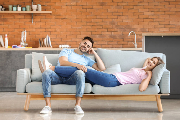 Šťastný mladý pár odpočívajícím pohromadě na pohovce doma - Fotografie, Obrázek