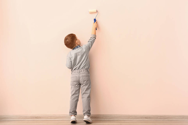 Симпатичный маленький мальчик рисует стену в комнате - Фото, изображение