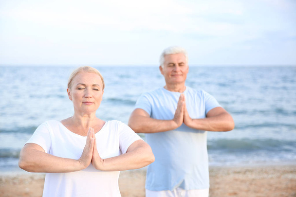 Älteres Paar praktiziert Yoga im Seebad - Foto, Bild