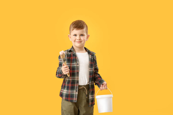 Aranyos kisfiú ecsettel és a vödör festék színes háttér - Fotó, kép