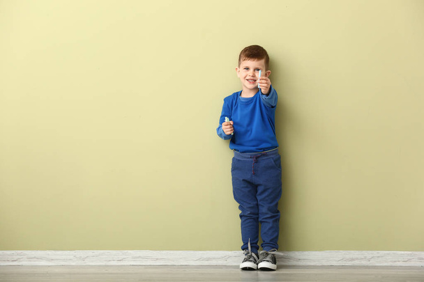 Lindo niño pequeño con lápices de colores cerca de la pared
 - Foto, imagen