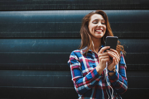 Junge erfolgreiche Frau nutzt Smartphone vor urbanem Hintergrund - Foto, Bild