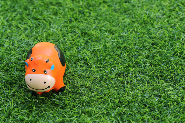 cute toy cow on grass, using as background - Photo, Image