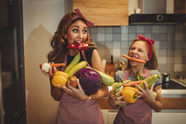 Happy mother and daughter having fun in making healthy meal at home kitchen - Foto, imagen
