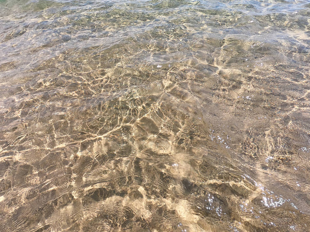 De textuur van helder water met zanderige bodem. Natuurlijke natuurlijke achtergrond. Toerisme en reizen - Foto, afbeelding