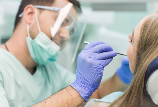 Close-up picture of young woman sitting in the dentists chair with opened mouth at dentists office while having examination - Foto, Bild