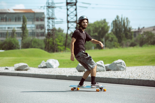 Skateboarder doing a trick at the citys street in sunny day - Zdjęcie, obraz