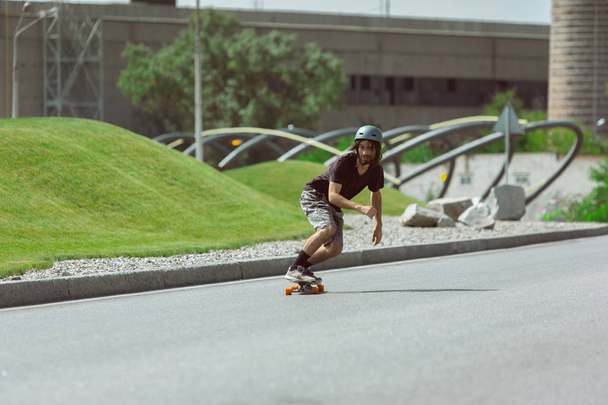 Skateboarder doing a trick at the citys street in sunny day - Φωτογραφία, εικόνα