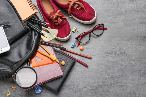 Verschiedene Schulsachen, Schuhe und Rucksack auf grauem Hintergrund - Foto, Bild